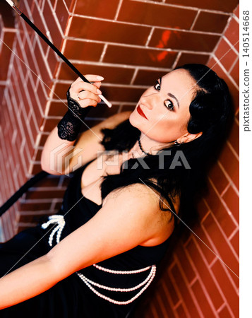 Flapper woman holding cigarette holder in vintage 1920s style mafia game Flapper woman holding cigarette holder in vintage 1920s style mafia game 140514668