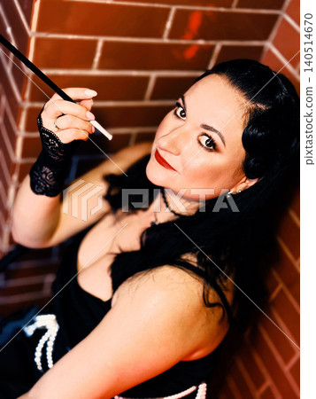 Stylish woman holding cigarette holder portraying retro glamour Stylish woman holding cigarette holder portraying retro glamour 140514670