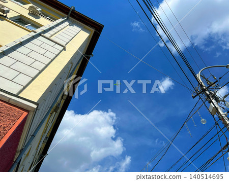 Low angle upward view of airplane in the sky between urban building corner and power lines Low angle upward view of airplane in the sky between urban building corner and power lines 140514695