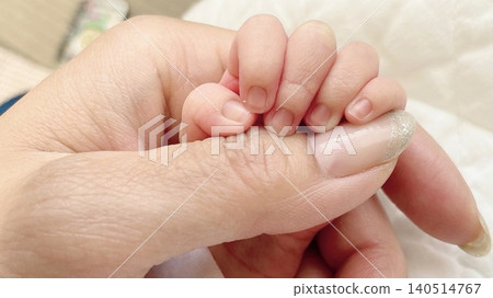 A heartwarming scene of parent-child interaction: a baby's tiny hand grasping an adult's finger (horizontal view). 140514767