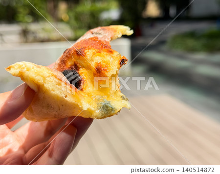 A half-eaten loaf of bread held in someone's hand. A pizza-style bread topped with Gorgonzola cheese and honey and baked. 140514872
