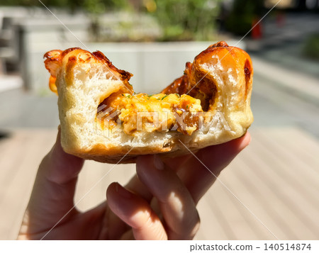 A freshly baked curry bun held by hand. The cross-section of the soft bread, which is made to encase the curry sauce. A freshly baked curry bun held by hand. The cross-section of the soft bread, which is made to encase the curry sauce. 140514874