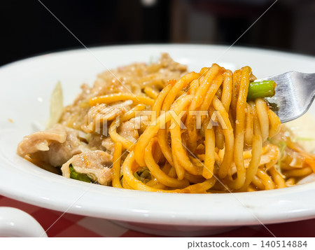 A plate with Neapolitan spaghetti and ginger-fried pork. The person is lifting the Neapolitan spaghetti with chopsticks. A plate with Neapolitan spaghetti and ginger-fried pork. The person is lifting the Neapolitan spaghetti with chopsticks. 140514884