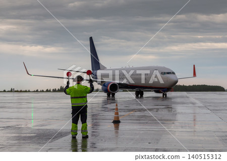 Airplane marshalling at the aiport in rainy weather. Passenger airliner meeting 140515312