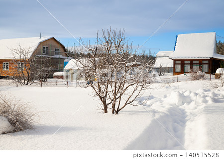 Rural country house and shed covered in deep snow and drifts after a blizzard. Winter landscape in the village on a sunny day. Rural country house and shed covered in deep snow and drifts after a blizzard. Winter landscape in the village on a sunny day. 140515528