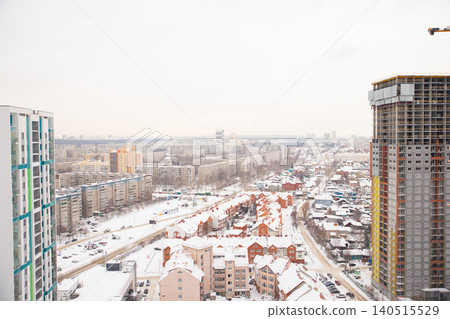 Snow covered cityscape of residential buildings and streets during winter in an urban area under gray skies. city panorama, street, townhouse, houses, buildings. Aerial view Snow covered cityscape of residential buildings and streets during winter in an urban area under gray skies. city panorama, street, townhouse, houses, buildings. Aerial view 140515529