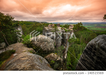 Rock city formations in Hruba Skala, Bohemian Paradise (Cesky raj), rising from forest seen from above. Orange sunrise sky lights sandstone towers and valleys panoramic view sky . Rock city formations in Hruba Skala, Bohemian Paradise (Cesky raj), rising from forest seen from above. Orange sunrise sky lights sandstone towers and valleys panoramic view sky . 140515569