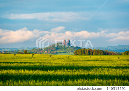 Panoramic view of Bohemian Paradise landscape with Trosky Castle ruin rising above hills, soft sunset light, dramatic clouds and light mist, barley fields in foreground landscapes Panoramic view of Bohemian Paradise landscape with Trosky Castle ruin rising above hills, soft sunset light, dramatic clouds and light mist, barley fields in foreground landscapes 140515591