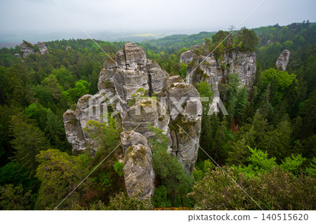 Rock city formations in Hruboskalsko, Bohemian Paradise (Cesky raj), Czech Republic, with peaks of giant sandstone rocks and cliffs emerging from light morning mist panoramic view Rock city formations in Hruboskalsko, Bohemian Paradise (Cesky raj), Czech Republic, with peaks of giant sandstone rocks and cliffs emerging from light morning mist panoramic view 140515620