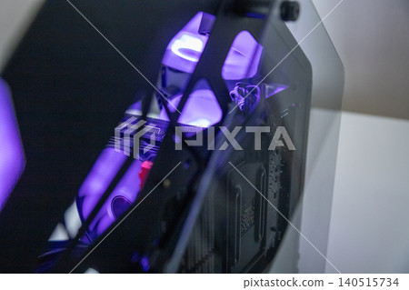 Gaming computer case with purple glowing interior. Desktop PC tower with LED lighting and glass side panel. Hardware components for high performance gaming build and technology concept. Gaming computer case with purple glowing interior. Desktop PC tower with LED lighting and glass side panel. Hardware components for high performance gaming build and technology concept. 140515734