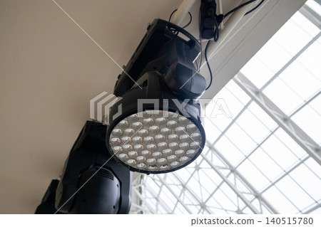 Professional rotating LED spotlight mounted on ceiling structure. Stage lighting equipment for concert, studio production and event performance. Industrial technology for show illumination. Professional rotating LED spotlight mounted on ceiling structure. Stage lighting equipment for concert, studio production and event performance. Industrial technology for show illumination. 140515780