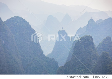 Misty mountains rise sharply against a soft, hazy sky Misty mountains rise sharply against a soft, hazy sky 140516570