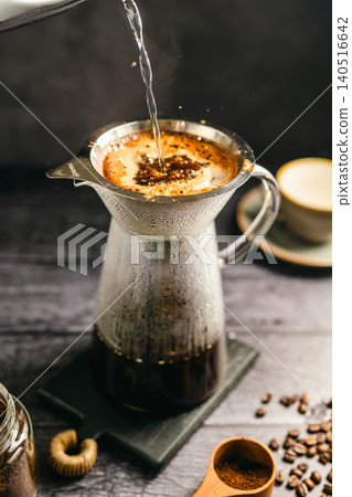 Pour hot water over coffee brewing with dripper and kettle, specialty coffee preparation, dark background, still life Pour hot water over coffee brewing with dripper and kettle, specialty coffee preparation, dark background, still life 140516642