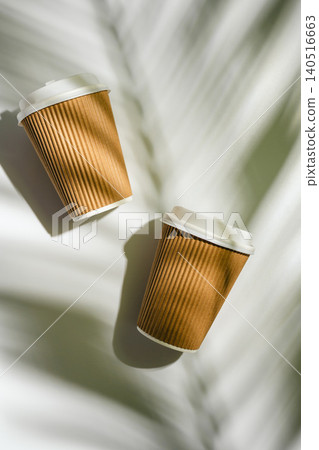 Two takeaway coffee cups with palm leaf shadows on white background, flat lay with copy space Two takeaway coffee cups with palm leaf shadows on white background, flat lay with copy space 140516663