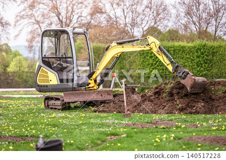 Compact excavator working in garden yard landscaping and ground preparation Compact excavator working in garden yard landscaping and ground preparation 140517228