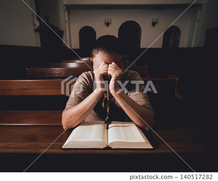 Christian woman praying in church. Hands crossed and Holy Bible on wooden desk. Christian woman praying in church. Hands crossed and Holy Bible on wooden desk. 140517282