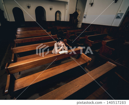 Christian woman praying in church. Hands crossed and Holy Bible on wooden desk. Christian woman praying in church. Hands crossed and Holy Bible on wooden desk. 140517283