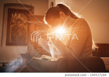 Christian woman praying in church. Hands crossed and Holy Bible on wooden desk. Christian woman praying in church. Hands crossed and Holy Bible on wooden desk. 140517284