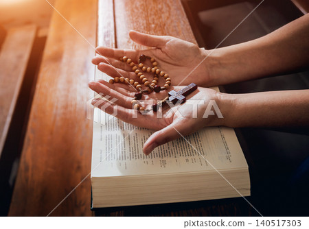 Christian woman praying in church. Hands crossed and Holy Bible on wooden desk. Christian woman praying in church. Hands crossed and Holy Bible on wooden desk. 140517303