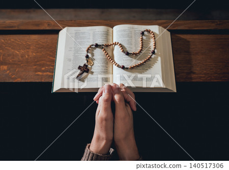 Christian woman praying in church. Hands crossed and Holy Bible on wooden desk. Christian woman praying in church. Hands crossed and Holy Bible on wooden desk. 140517306