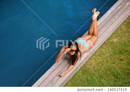 Woman, aerial or tanning at swimming pool to relax, rest or chill in summer holiday vacation in Hawaii. Calm girl, break and zen female person sunbathing in a spa at resort, home or hotel for peace Woman, aerial or tanning at swimming pool to relax, rest or chill in summer holiday vacation in Hawaii. Calm girl, break and zen female person sunbathing in a spa at resort, home or hotel for peace 140517410
