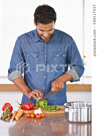 Cooking, man and cutting vegetables on kitchen counter for healthy diet, nutrition or lunch. Chopping board, food and vegan person preparing salad for dinner, meal and organic ingredients in home 140517437