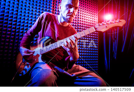 Young man playing on the guitar in sound recording studio. Young man playing on the guitar in sound recording studio. 140517509