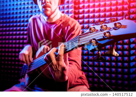 Young man playing on the bass guitar in sound recording studio. Young man playing on the bass guitar in sound recording studio. 140517512