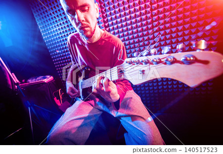 Young man playing on the guitar in sound recording studio. Young man playing on the guitar in sound recording studio. 140517523