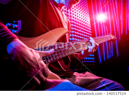 Young man playing on the bass guitar in sound recording studio. Young man playing on the bass guitar in sound recording studio. 140517524