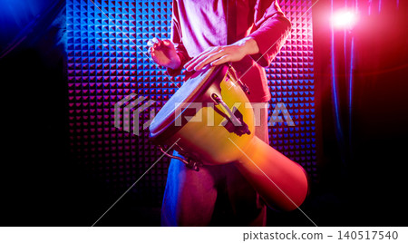 Young man playing on djembe in sound recording studio. Young man playing on djembe in sound recording studio. 140517540