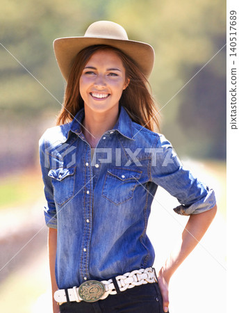 Happy woman, portrait and cowgirl with hat on farm for adventure, travel or outdoor journey in Texas. Female person with smile in western fashion, denim shirt and cap at ranch in the countryside 140517689