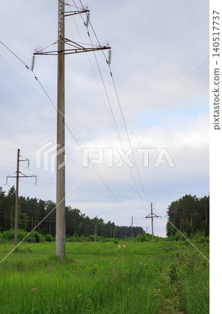 Power transmission lines stretching from substation across green field, concrete utility poles in countryside landscape Power transmission lines stretching from substation across green field, concrete utility poles in countryside landscape 140517737