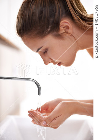 Woman, house and hygeine for washing face, skincare and sink in self care and beauty with smile in restroom. Female person, clean water and tap in bathroom, morning and happy for health at home 140517958