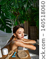 Caucasian young woman applying body scrub in bright modern home bathroom spa 140518060