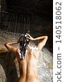 Caucasian young adult woman washing wet hair under rain shower in modern stone bathroom 140518062