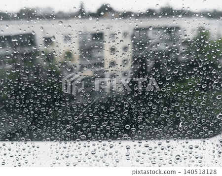 Raindrops on a window glass with a blurred city street background in rainy weather Raindrops on a window glass with a blurred city street background in rainy weather 140518128