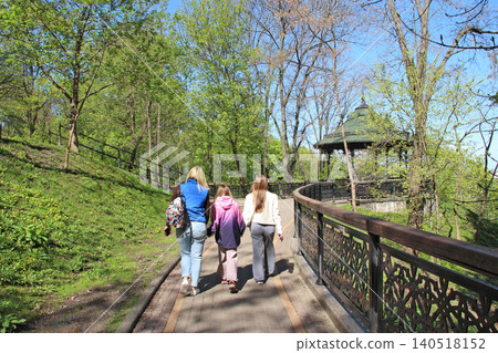 Three girls walking along path in green spring park towards vintage gazebo Three girls walking along path in green spring park towards vintage gazebo 140518152