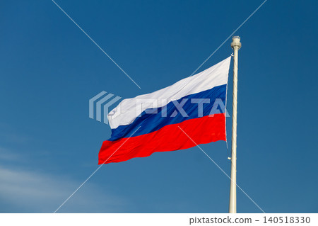 Close up of national flag of Russian Federation with white, blue, and red stripes waving on flagpole against clear blue sky on sunny day Close up of national flag of Russian Federation with white, blue, and red stripes waving on flagpole against clear blue sky on sunny day 140518330