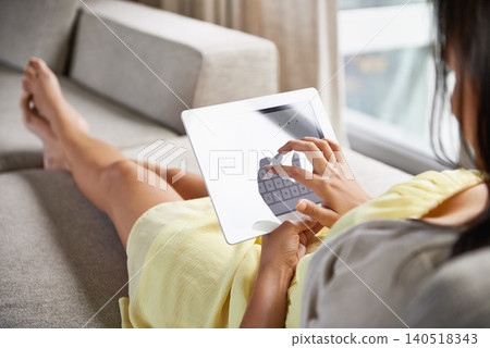 Woman, typing and tablet on sofa in home online with social media, communication or website. Reading, ebook and girl click screen for streaming, video or search for information on internet on couch 140518343