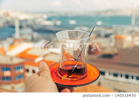 One fresh tea in Turkish teacup Armudu at bottom in woman's palm against backdrop of cityscape sunny Istanbul One fresh tea in Turkish teacup Armudu at bottom in woman's palm against backdrop of cityscape sunny Istanbul 140518450