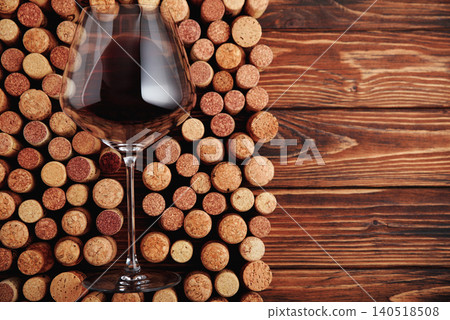 Red wine pouring in a glass standing on corks 140518508