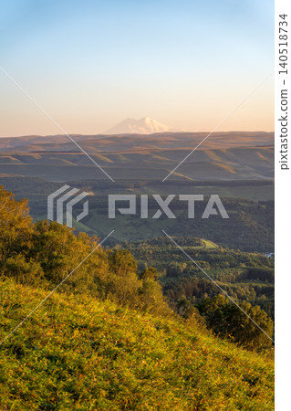 Panoramic view of the green valley and the snowy peak of Mount Elbrus on the horizon against the blue sky on a sunny clear morning in Kislovodsk Stavropol territory, Russia 140518734