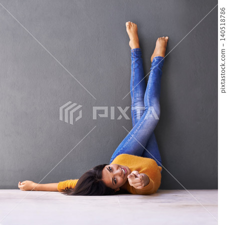 Woman, smile and wall background for point, feet on wall and relaxing on floor in portrait with fashion. Female person, choice and chill at home for happiness, hey you and wellness in jeans with toes Woman, smile and wall background for point, feet on wall and relaxing on floor in portrait with fashion. Female person, choice and chill at home for happiness, hey you and wellness in jeans with toes 140518786