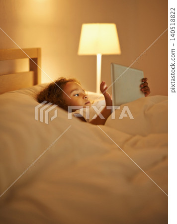 Internet, child and tablet in bed at night, comfortable and online for games or play in home. Female person, girl and rest in bedroom or lying to relax, website and streaming or app for entertainment 140518822