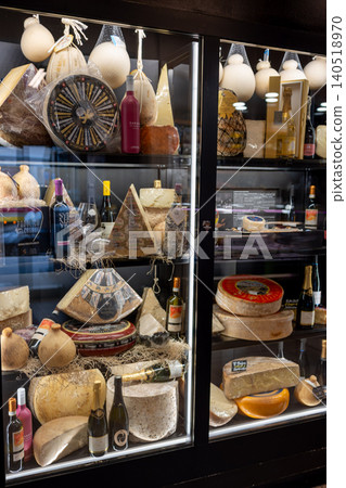 Milan, italy, october 2, 2024. Shop cabinet showcasing a wide selection of traditional italian cheeses and bottles of wine, offering a gourmet food experience Milan, italy, october 2, 2024. Shop cabinet showcasing a wide selection of traditional italian cheeses and bottles of wine, offering a gourmet food experience 140518970