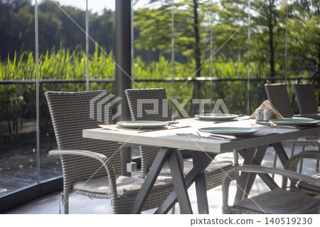 Served restaurant table on terrace with wicker chairs and scenic nature view Served restaurant table on terrace with wicker chairs and scenic nature view 140519230