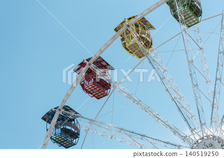 Colorful ferris wheel cabins against a clear blue sky on a sunny day Colorful ferris wheel cabins against a clear blue sky on a sunny day 140519250