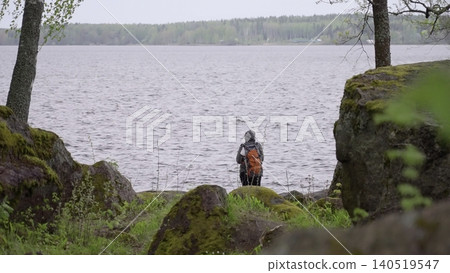 Serene Explorer Observes Tranquil Landscape. Mountain Trekker Studies Silent Lake Surroundings Calmly. Creative 140519547