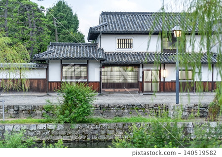 A beautiful, imposing traditional wooden building with latticed windows and white walls stands over the stone wall of the Kurashiki River (Kurashiki City, Okayama Prefecture). A beautiful, imposing traditional wooden building with latticed windows and white walls stands over the stone wall of the Kurashiki River (Kurashiki City, Okayama Prefecture). 140519582